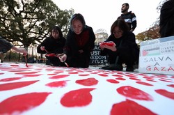 パレスチナ自治区ガザ地区の犠牲者を悼み、赤い涙を描く人たち＝広島市中区の平和記念公園で2023年11月29日、中川祐一撮影