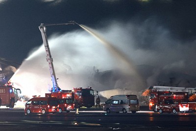 煙を上げる機体に放水する消防車両＝羽田空港で2024年1月2日午後10時半、渡部直樹撮影