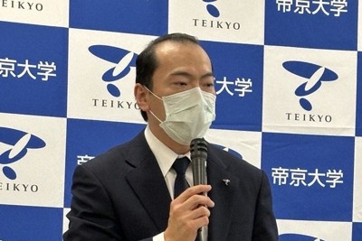 記者会見であいさつをする冲永佳史理事長・学長