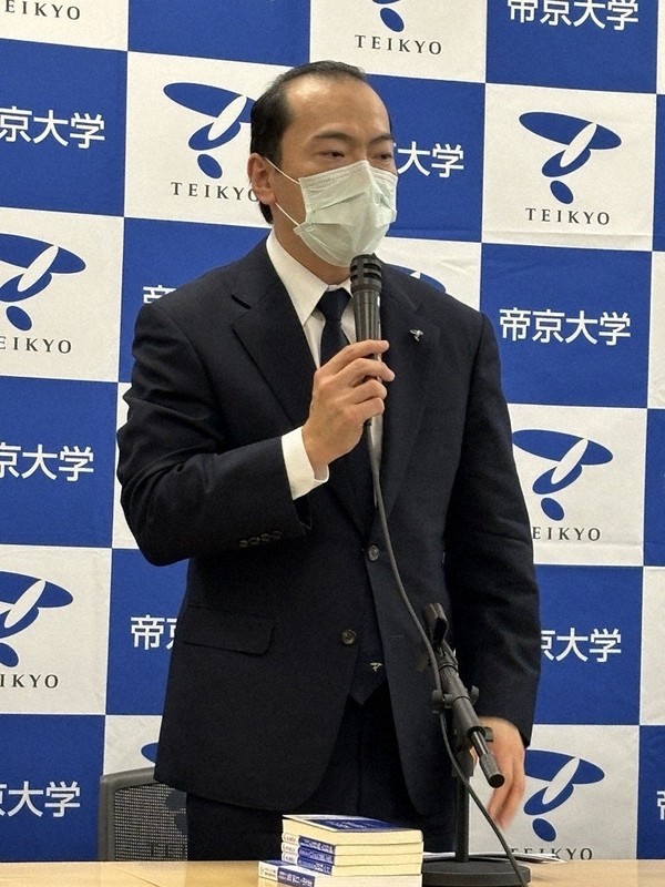 記者会見であいさつをする冲永佳史理事長・学長