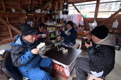 土砂崩れによる道路寸断で孤立した下山町で、小屋に集まって食事をする浦本晃さん（奥左）と近隣住民ら。昼間は集まって過ごし、夜は車中泊しているという＝石川県輪島市で2024年1月10日、北山夏帆撮影