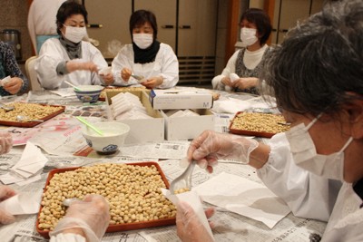 スプーンを使い、節分の豆を袋に詰める女性たち＝静岡県三島市の三嶋大社で2024年1月16日、石川宏撮影