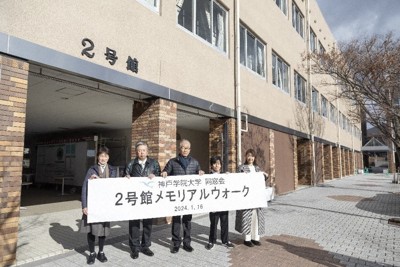 解体される2号館前で「メモリアルウオーク」の横断幕を掲げる同窓生ら