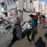 イスラエル軍の空爆で破壊された住宅の近くを歩く市民＝パレスチナ自治区ガザ地区南部ラファで1月1日、ロイター