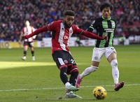 Sheffield's Jayden Bogle, left, and Brighton's Kaoru Mitoma challenge for the ball during the English Premier League soccer match between Sheffield United and Brighton and Hove Albion at Bramall Lane stadium, Sheffield, England, on Feb. 18, 2024. (Nick Potts/PA via AP)