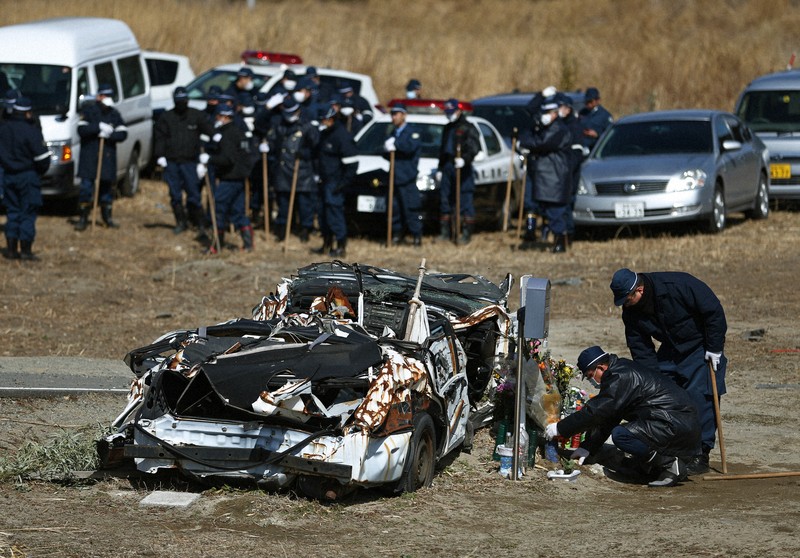 行方不明者の一斉捜索を前に、殉職した2人が乗っていたパトカーに献花する警察官ら＝福島県富岡町で2014年3月11日、小出洋平撮影