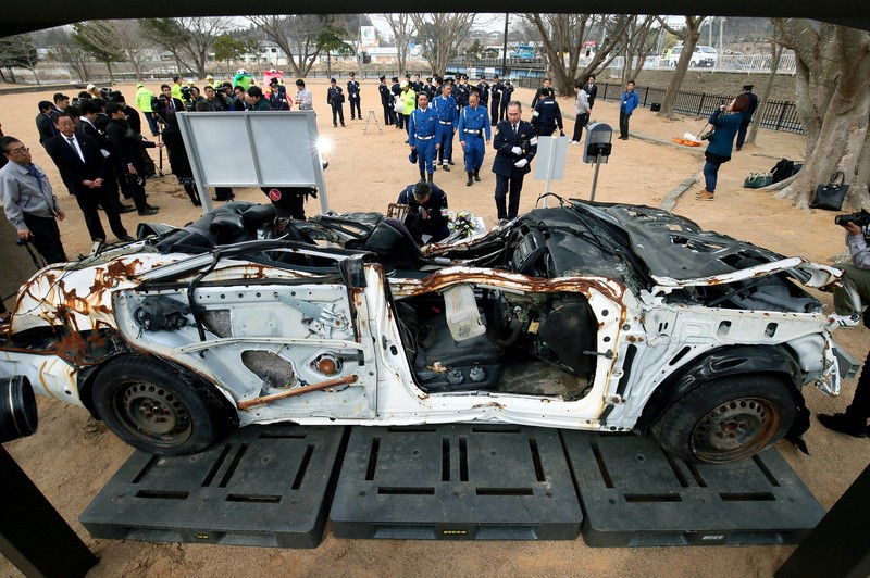 公園に移設された被災パトカーに献花する行方不明の警察官の同僚ら＝福島県富岡町で2015年3月16日、森田剛史撮影