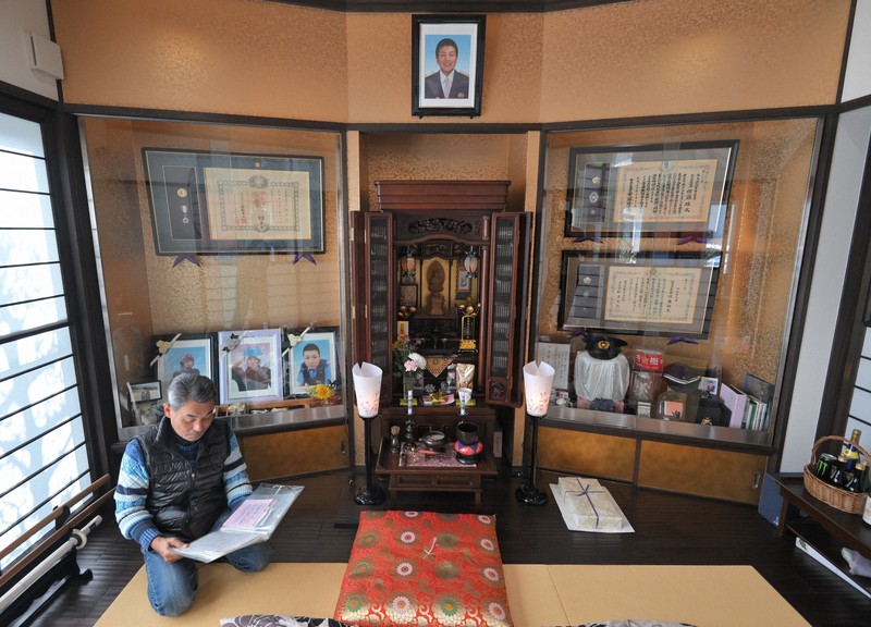 佐藤雄太さんへ宛てられた手紙を読む、父の安博さん。パトカーの横に設置されたポストには、約1000通もの手紙が寄せられたという＝福島市で2024年2月2日、手塚耕一郎撮影