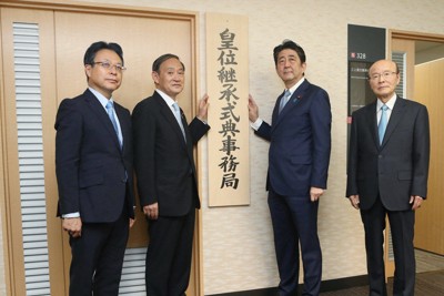 皇位継承式典事務局の看板を掛ける安倍晋三首相（中央右）と菅義偉官房長官（同左）。左端は山崎重孝事務局長、右端は杉田和博官房副長官（肩書はいずれも当時）＝内閣府で2018年8月1日（代表撮影）