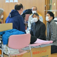 能登半島地震の避難所を訪問され、被災した新谷満さん（左手前）、千恵子さん（左端）親子に声をかける天皇、皇后両陛下。奥は坂口茂輪島市長＝石川県輪島市のふれあい健康センターで2024年3月22日午後1時55分、手塚耕一郎撮影
