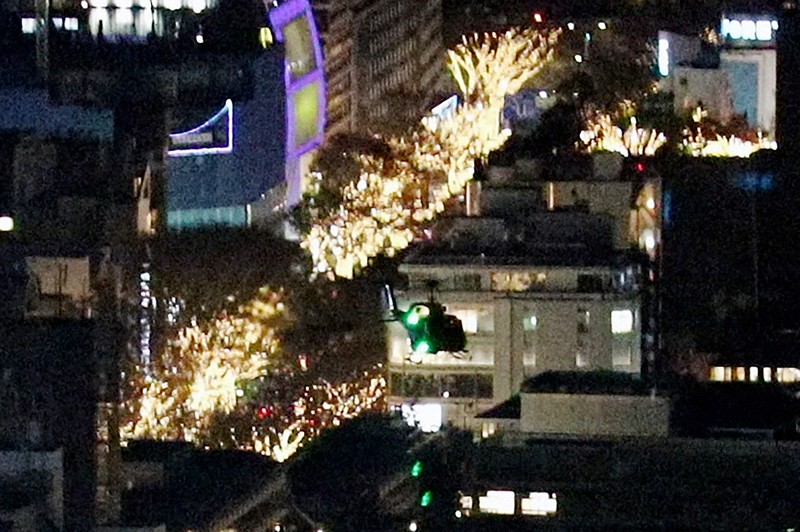 東京・六本木にある米軍ヘリポートへの着陸に向けて、イルミネーションの輝く表参道周辺を通過した米空軍ヘリ「UH1」（手前）＝2022年12月6日午後7時48分ごろ、都心の200メートル級のビルより取材班が撮影した動画から