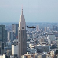 ハリス米副大統領の随行者らを乗せて東京・代々木駅近くの「NTTドコモ代々木ビル」（高さ約270メートル）の手前を通過する米陸軍ヘリ「ブラックホーク」の編隊。編隊の下に原宿・表参道エリアの市街地が広がる＝2022年9月28日午後4時34分ごろ、都心の200メートル級のビルより取材班が撮影した動画から