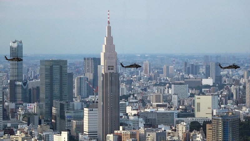ハリス米副大統領の随行者らを乗せて東京・代々木駅近くの「NTTドコモ代々木ビル」（高さ約270メートル）の手前を通過する米陸軍ヘリ「ブラックホーク」の編隊。編隊の下に原宿・表参道エリアの市街地が広がる＝2022年9月28日午後4時34分ごろ、都心の200メートル級のビルより取材班が撮影した動画から