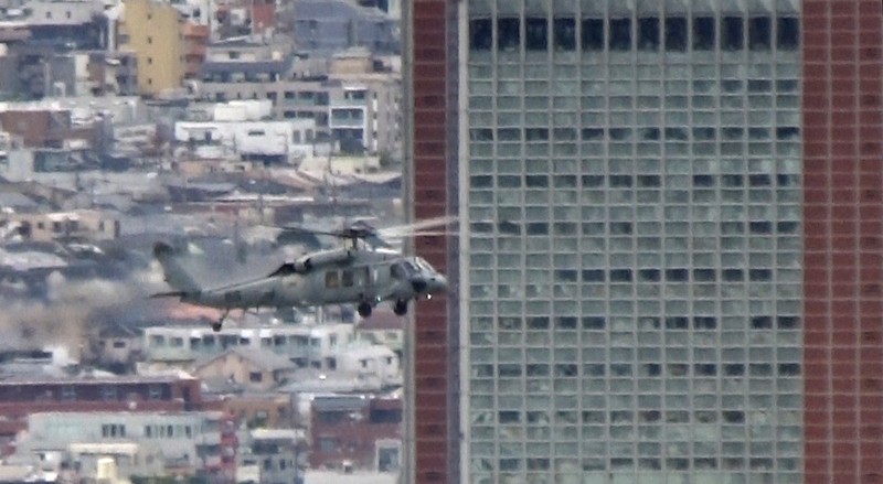 東京都世田谷区太子堂の「キャロットタワー」（高さ124メートル）手前を通過する米海軍ヘリ「シーホーク」＝都内で2020年12月14日午後1時25分ごろ、大場弘行撮影（写真は動画から）