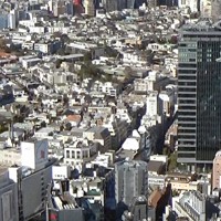 東京・渋谷駅前の渋谷センター街上空を、日本のヘリであれば航空法違反にあたる低空で通過する米海軍ヘリ「シーホーク」（写真右上）。ヘリの奥側にある黒いビルは高さ約111メートル。左下には東急百貨店本店が見える＝東京都内で2020年12月17日、大場弘行撮影（写真は動画から）