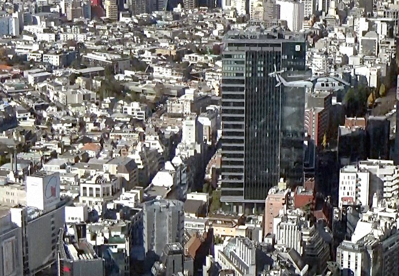 東京・渋谷駅前の渋谷センター街上空を、日本のヘリであれば航空法違反にあたる低空で通過する米海軍ヘリ「シーホーク」（写真右上）。ヘリの奥側にある黒いビルは高さ約111メートル。左下には東急百貨店本店が見える＝東京都内で2020年12月17日、大場弘行撮影（写真は動画から）