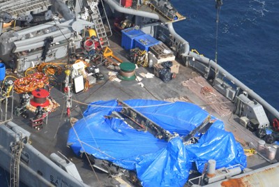 米軍のサルベージ船に引き揚げられたオスプレイの機体胴体部らしき物体＝鹿児島県・屋久島沖で2023年12月27日午前11時13分、本社ヘリから上入来尚撮影