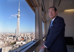 オフィスで窓辺に立つ福地茂雄さん＝東京都墨田区で2013年10月11日、手塚耕一郎撮影