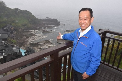 「ランプの宿」や海底隆起した入り江を望む展望台に立つ刀祢秀一さん＝石川県珠洲市で、国本ようこ撮影