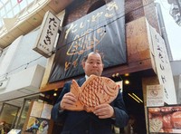 「たいやき ともえ庵」オーナーの辻井啓作さん。持っているのは同店で企画販売しているたい焼きのクッション＝本人提供