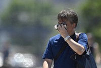 A man walks while wiping sweat off his face in Tokyo's Chiyoda Ward, in this July 2023 file photo. (Mainichi/Tatsuya Fujii)
