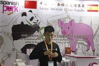 A promoter at a booth for imported Spanish pork prepares for another day at the China International Import Expo in Shanghai, on Nov. 6, 2018. (AP Photo/Ng Han Guan)