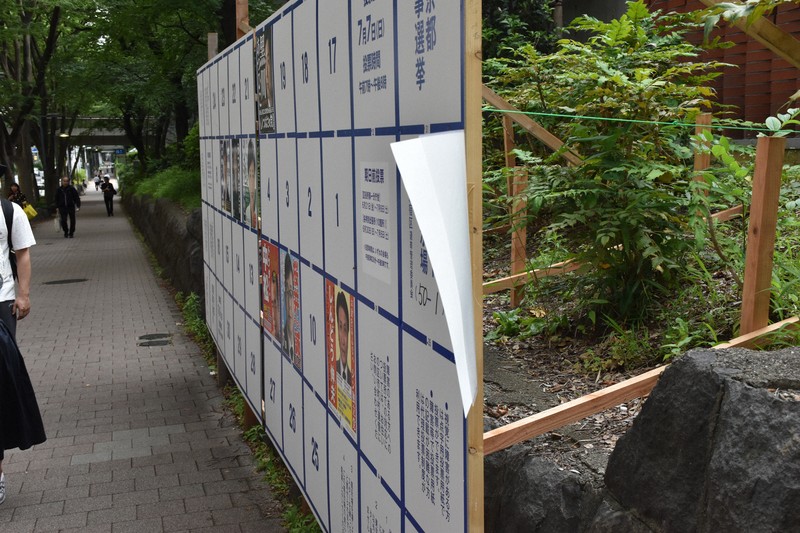 画びょうで留められたクリアファイル入りの候補者ポスター（右端）。風にひらひらと揺れていた＝東京都新宿区で2024年6月20日午後4時7分、田中綾乃撮影