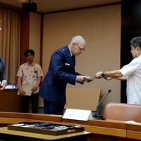 第18航空団司令官のニコラス・エバンス准将（右から2人目）とマシュー・ドルボ在沖縄米国総領事（左）に抗議文を手渡す沖縄県の池田竹州副知事（右）＝沖縄県庁で2024年6月27日午前9時37分、喜屋武真之介撮影
