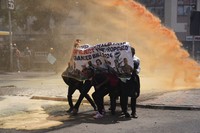 Protesters hide behind a banner as Kenya police spray a water cannon at them during a protest over proposed tax hikes in a finance bill in downtown Nairobi, Kenya, on June 25, 2024. (AP Photo/Brian Inganga) 