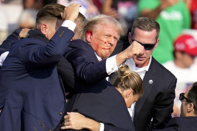 演説中に銃撃されて流血し、警護担当者らに支えられるトランプ前米大統領（中央）＝米東部ペンシルベニア州バトラーで2024年7月13日、AP