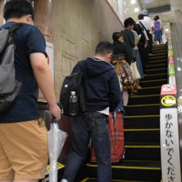 エスカレーターの左側に立ち、歩く人のために「片側空け」をする利用者＝名古屋市中区で2023年10月、酒井志帆撮影