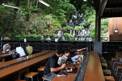 滝のせせらぎの中で湧水の流しそうめんを味わえる吾妻庵。非日常空間を演出する＝福島市佐原で2024年7月4日、錦織祐一撮影