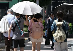 強い日差しの中、日傘を差すなどして歩く人たち＝福岡市中央区で2024年7月3日午後2時22分、平川義之撮影