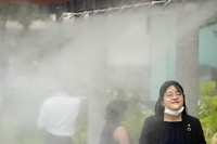 People cool off at a cooling mist spot in Tokyo on July 4, 2024. (AP Photo/Shuji Kajiyama, File)