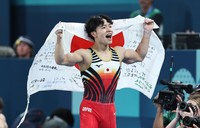 Shinnosuke Oka holds up a Japanese flag after winning the men's artistic gymnastics individual all-around final at the Paris Olympics on July 31, 2024, at Bercy Arena in Paris. He also clinched three more medals, with two gold in the men's team and horizontal bar events, and one bronze in the parallel bars event. (Mainichi/Tatsuro Tamaki)