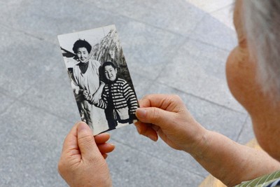 母と弟の写真をみつめる中村政子さん＝札幌市中央区で2024年8月9日、金将来撮影
