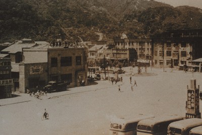 整備された徳島駅前広場から南西方面の町並み。1950年ごろの撮影とみられる。中央の3階建ての建物は徳島市内町小学校で、終戦直後には手前の道路付近に多くの店があったという。背後に見える山並みは眉山（徳島県立文書館提供）