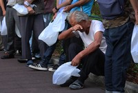 A homeless man sits on the curb and wipes his brow during an Aug. 12, 2024, food handout by the Ogimachi Park soup kitchen association in the city of Osaka, as temperatures stayed above 30 degrees Celsius even in the late afternoon. (Mainichi/Daiki Takikawa)