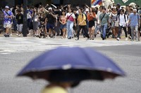 People walk along Shibuya scramble crossing under hot and sunny weather, on Aug. 28, 2024, in Tokyo. (AP Photo/Eugene Hoshiko)
