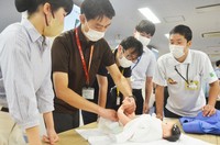 助産師のアドバイスを受けながらおむつの交換体験をする愛媛県庁の男性職員たち＝松山市で2023年8月8日、山中宏之撮影