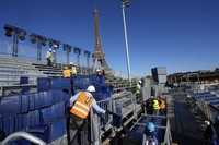 Workers remove grandstand seating as part of the dismantling of the Olympic venue the "Stade Tour Eiffel" with the Eiffel tower in the background in Paris, on Sept. 13, 2024. (AP Photo/Michel Euler)