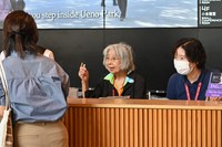Ninety-six-year-old Takako Ishii, center, assists foreign visitors at the Asakusa Culture Tourist Information Center in Tokyo's Taito Ward on Aug. 12, 2024. (Mainichi/Eri Misono)