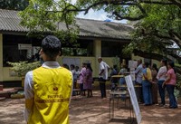 An election monitor watches voters waiting in queue at a polling center during the presidential election on the outskirts of Colombo, Sri Lanka on Sept. 21, 2024.(AP Photo/Rajesh Kumar Singh)