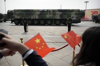 Spectators wave Chinese flags as military vehicles carrying DF-41 nuclear ballistic missiles roll by during a parade to commemorate the 70th anniversary of the founding of Communist China, in Beijing on Oct. 1, 2019. (AP Photo/Mark Schiefelbein, File) 