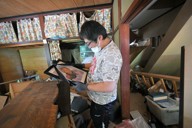 祖母の遺影を見つめる谷内勝次さん。元の場所から流され傾いた自宅の2階で見つけた＝石川県輪島市打越町で2024年9月30日、手塚耕一郎撮影