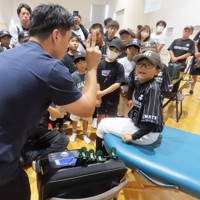 野球スクールの説明会で、スタッフから施設に備えられた機器などの話を聞く小学生ら＝岩手県花巻市で2024年9月7日午前10時43分、早川健人撮影