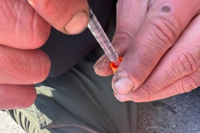 ヘロインとメタンフェタミンを混ぜて液体状にしたものを注射器で吸い上げる男性＝米東部フィラデルフィア市ケンジントン地区で2024年6月25日、中村聡也撮影