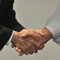 公示前、集会で支援者と握手を交わす立候補予定者（左）＝大分市で