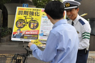 自転車のながらスマホの厳罰化について説明する愛知県警の警察官＝名古屋市内で2024年10月17日午後3時39分、田中理知撮影