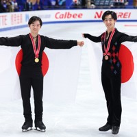 男子の表彰式後に日の丸を背にする優勝した鍵山優真（左）と壷井達也＝国立代々木競技場で2024年11月9日、猪飼健史撮影